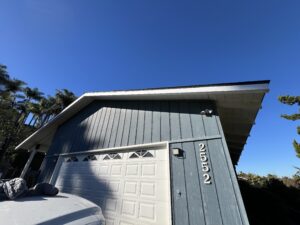 A blue house with white trim and the numbers 2552 by the garage, under a clear blue sky. A white vehicle is partially visible in front.