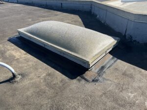 A frosted, dome-shaped skylight is installed on a flat rooftop with visible sealant around its base.
